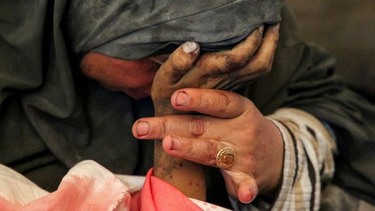 La palestina Buthayna Abu Jazar llora mientras sujeta la mano de su hijo Hazma, muerto en un ataque israelí, el jueves en Rafah.