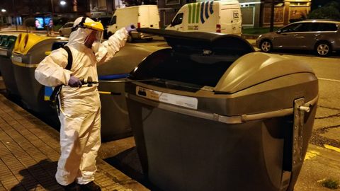 Un operario de Emulsa desinfecta un contenedor en una calle de Gijn