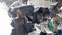 Tres jóvenes luchan contra el viento con sus paraguas en Santiago.