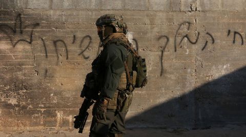 Fuerzas militares israels paseando al lado de una pintada en ebreo que dice Vivir por el Rey Cristo