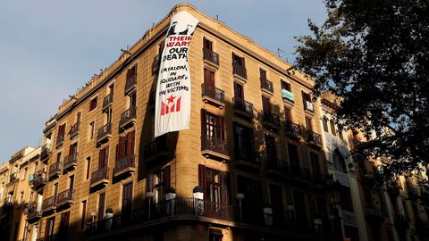 El movimiento soberanista ha colgado una segunda pancarta en la fachada de un edificio de La Rambla de Barcelona, donde en breve se celebrará una ofrenda floral a las víctimas de los atentados del 17A, en la que puede verse una imagen del Rey Felipe VI y del de Arabia Saudí estrechándose las manos.