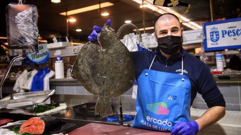 Un placero sostiene un rodaballo, un pescado que escasea estos días en el mercado