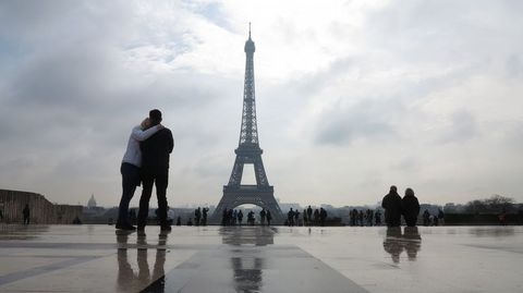 Una pareja se besa delante de la Torre Eiffel. 