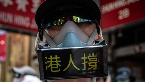 Un manifestante, cubierto por una mascarilla y utilizando su móvil a modo de pancarta, en las protestas contra la ley de seguridad nacional en Hong Kong