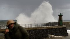 Una mujer se protege de una gran ola que se estrella contra el puerto de Viavelez