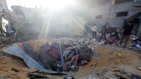 Varios palestinos inspeccionan el lugar donde un misil israel impact contra una vivienda, en Rafah
