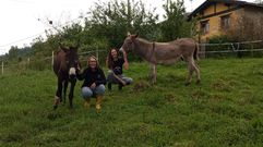 Eva y Lonneke posan para la foto con los dos burros que cuidan