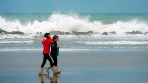Dos personas pasean junto a un fuerte oleaje en la playa de Benicasim