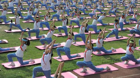 Estudiantes practican yoga en un campus de Jinan, en la provincia china de Shandong