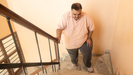 Una persona con obesidad intentando subir unas escaleras.