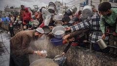 Varios palestinos se apiñan para conseguir un poco de comida en Rafah.