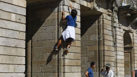 Peregrino escalando un tramo de la fachada del Pazo de Raxoi, la sede del Concello de Santiago y de la Xunta de Galicia