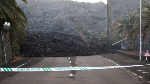 Una cinta de la Guardia Civil mantiene cortada una carretera bloqueada por la lava arrojada por el volcán en La Laguna