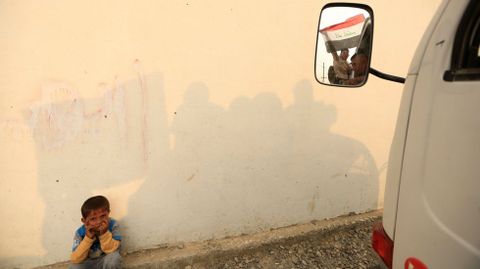 Un nio sentado junto a una furgoneta en un campo de refugiados en las afueras de Erbil, en Irak
