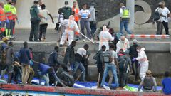 La imagen es de inmigrantes desembarcando de uno de los dos cayucos que llegaron este jueves con más de 200 personas a bordo al puerto de La Restinga, en la isla de El Hierro.