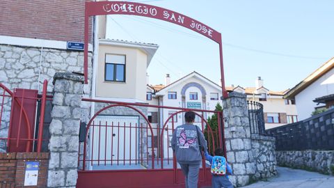 Dos personas frente a la entrada del colegio San José de Astillero, en Guarnizo, El Astillero, Cantabria. El centro lleva dos denuncias por la difusión en un chat de alumnos de fotos y vídeos de pornografía infantil.