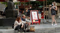 Una pareja de turistas fuma, con la mascarilla bajada, en el centro de Oviedo