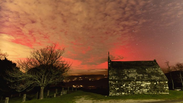 Una aurora boreal ilumina el cielo sobre el monte de San Nomedio en As Neves