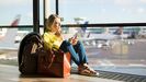 Una mujer consulta su teléfono móvil en una sala de aeropuerto