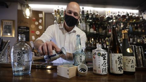 Un barman muestra diferentes botellas de «sake», bebida típica japonesa