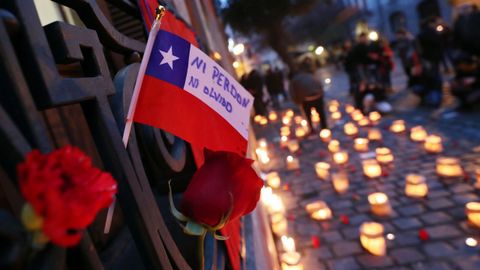 Una bandera chilena junto a velas encendidas para recordar el 44 aniversario del golpe de Estado de Pinochet (Chile).