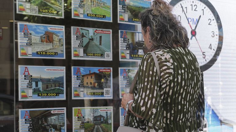 Una mujer este lunes delante del escaparate de una agencia inmobiliaria en el centro de Oviedo