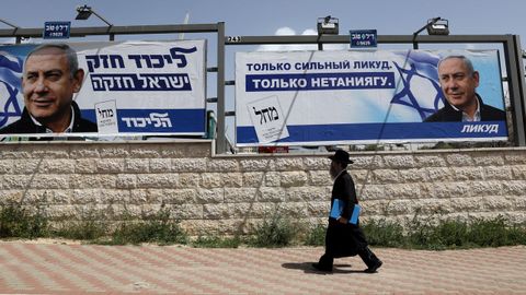 Un ultraortodoxo pasa por varios carteles electorales de Benjamin Netanyahu para las elecciones del martes