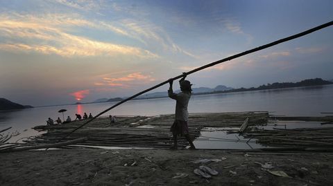 Varios trabajadores cargan con troncos de bamb en la orilla del ro Brahmaputra (India)