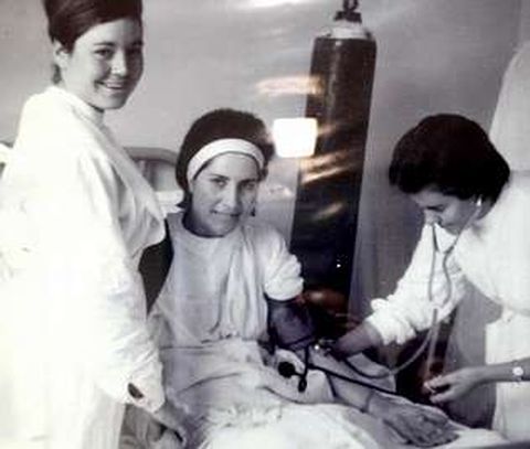 Personal de enfermera atendiendo a una paciente. Al fondo se ve una botella de oxgeno