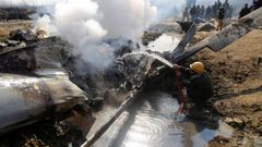 Un bombero apaga las llamas de uno de los aparatos derribados en el distrito de Bugdam