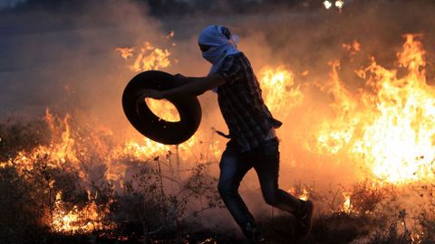 Un palestino huye del fuego durante las protestas contra Israel, despus del asesinato de un beb palestino de 18 meses