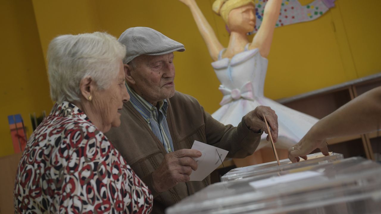 Una pareja de ancianos ejerce su derecho al voto en las elecciones generales en un colegio de Avils
