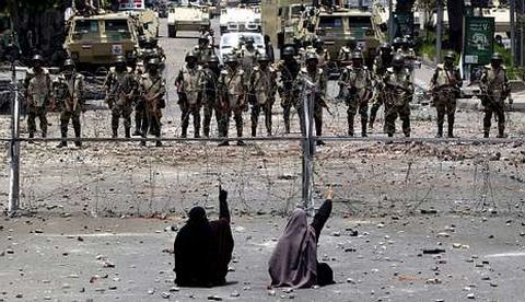 Miembros de los Hermanos Musulmanes permanecen sentados ante militares en El Cairo.