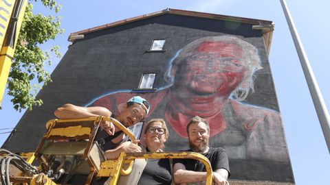 Tet Mareque, en el centro de la imagen, ante el edificio del barrio de Caranza en el que se ha plasmado su rostro. 