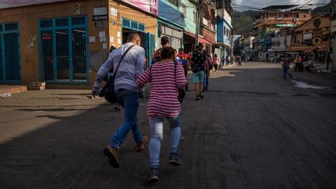 Un grupo de personas corren para refugiarse durante un tiroteo en el conflictivo barrio caraqueo de La Vega