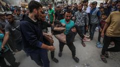 Un palestino rescata a un nio tras un bombardeo en Gaza.