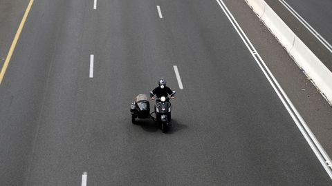 Un hombre con mascarilla conduce una moto en Israel