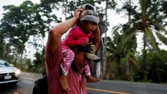 Un migrante hondureo trata de cubrir de la lluvia a su hija mientras camina por una carretera de Guatemala en direccin a Mexico 