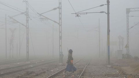 Una persona cruza las vas del tren entre una espesa niebla en Amristar (India).