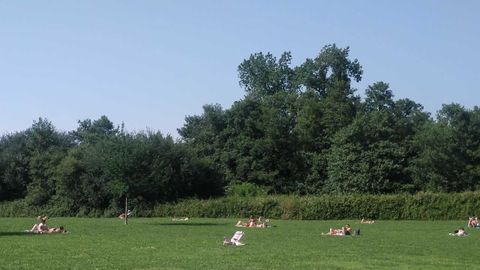 Diversas personas toman el sol en el Parque del Nora, en La Corredoria