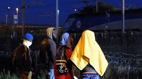 Varios inmigrantes esperan su oportunidad para cruzar el Eurotunel en Calais (Francia)