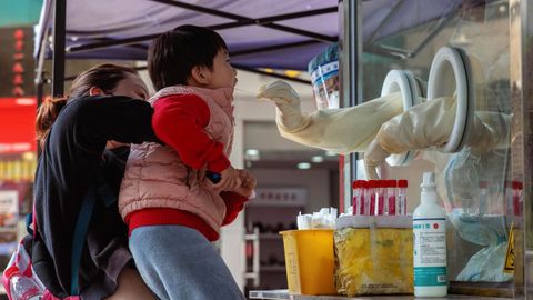 Un niño aupado por su madre se somete a una prueba covid en Shanghái