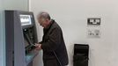 Un hombre de avanzada edad, saca dinero de un calero automático de una entidad bancaria en el centro de Oviedo