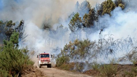 Un camin cargado de agua, entre el humo del incendio en una pista del monte comunal de A Ermida