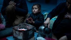 Marjan Hosini, de 3 aos, calienta sus manos al lado de sus padres, en un refugio temporal aledao al campamento de Moria