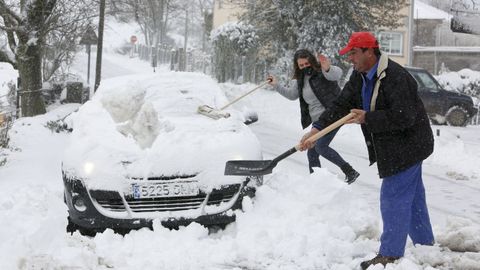 Vecinos de Hospital do Cebreiro intentan retirar un coche cubierto por la nieve para que pueda pasar la quitanieves