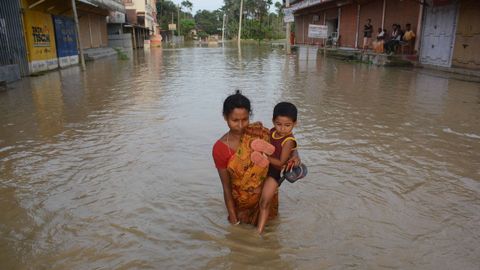 Una mujer intenta sacar a su hijo de una calle completamente inundada en India.