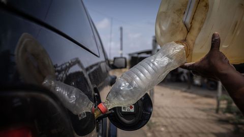 A person fills the tank of a vehicle with gasoline in Los Filuos, in the state of Zulia