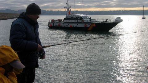 Pescadores recreativos practicando su aficin en la costa gallega, con una patrullera de la Guardia Civil al fondo, en una imagen de archivo. 