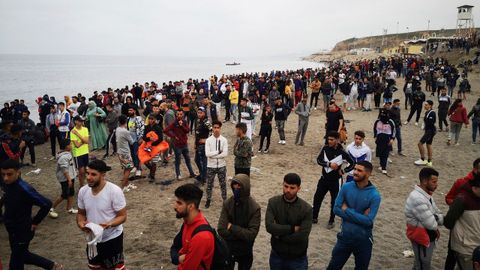 Cientos de personas esperan en la playa de la localidad de Fnideq (Castillejos), en Marruecos, para cruzar los espigones de Ceuta este martes en una avalancha de inmigrantes sin precedentes en España